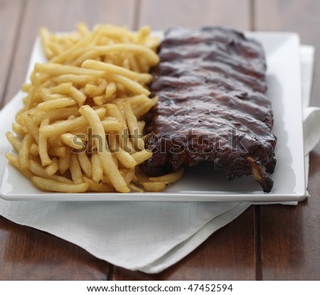 baked ribs with french fries on the side. Meat meal. Shallow depth of field.