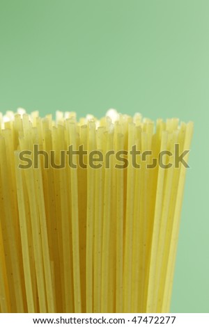 uncooked macro spaghetti pasta on a green background.
