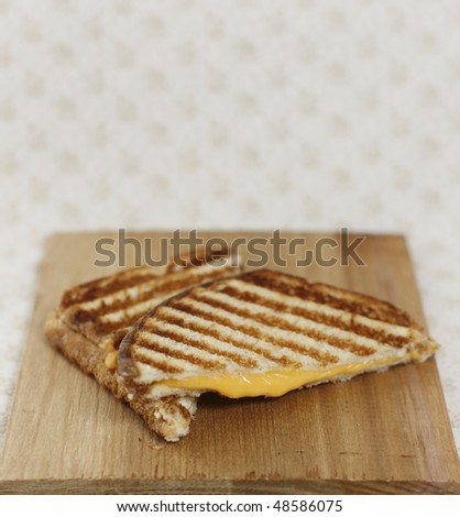 grilled cheese sandwich on a wooden board and a brown background.Lot of space to add text. Shallow depth of field.