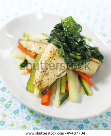 cooked mackerel fish meal with spinach on the top. Carrot and zukini below. Very shallow depth of field.