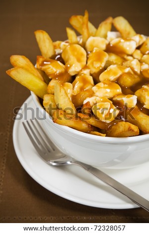 Poutine meal made with french fries, cheese curds and gravy. Very Shallow depth of field.