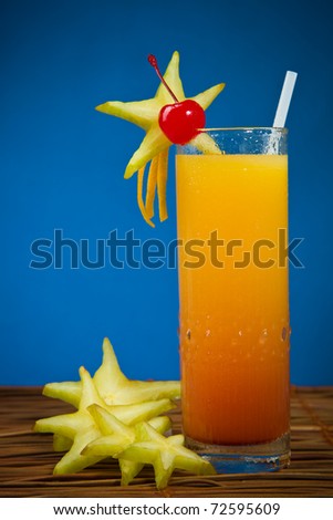 tropical drink with carambola, cherry and orange on a blue background. Shallow depth of field.