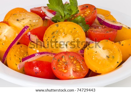 Appetizer salad with cherry tomato in a white bowl. Focus is on the yellow tomato in the center. Very shallow depth of field.