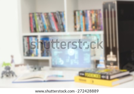Blurred background : Computer and book lying on a desk, in a room and front of a bookshelf
