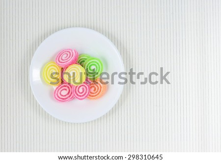 Assortment of colorful fruit roll jelly candy in white plate on bamboo pad plate,Top view