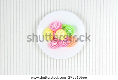 Assortment of colorful fruit roll jelly candy in white plate on bamboo pad plate,Top view