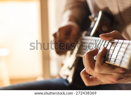 Practicing in playing guitar. Handsome young man playing guitar