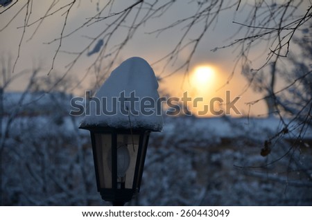 broken lamps with snow cap in winter at sunset in the park