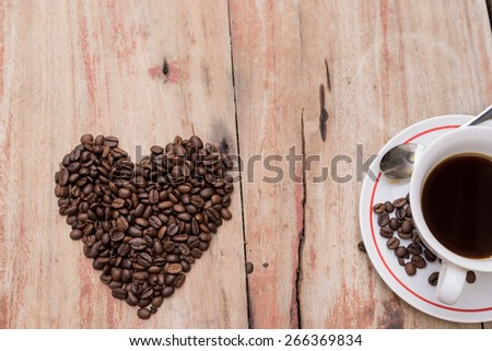cup of coffee and coffee beans heart on table