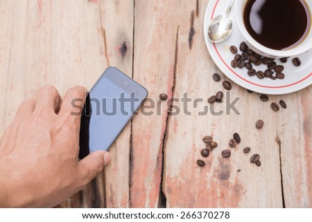 hold mobile phone and cup of coffee on table