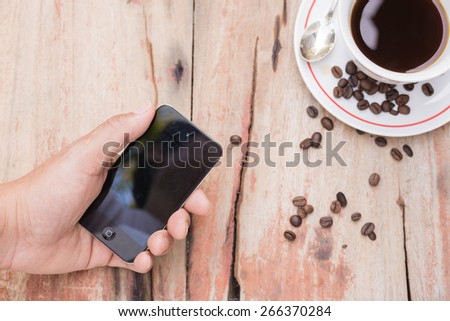 hold mobile phone and cup of coffee on table