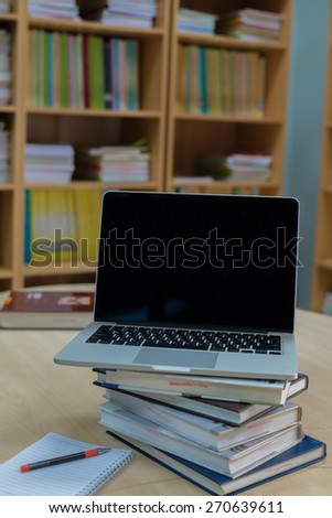Laptop and book on a desk in library
