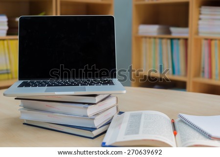 Laptop and book on a desk in library