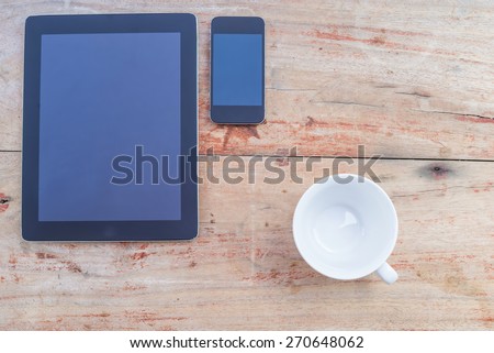 Tablet, cup and Smart phone. Mobile phone and Tablet pc on wooden table
