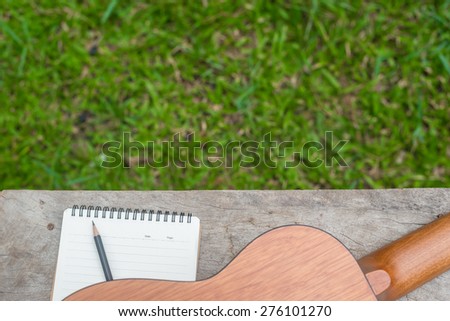 Guitar and Notebook on wood table, Writing music in the garden