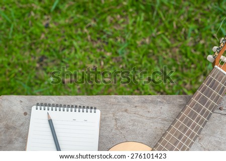 Guitar and Notebook on wood table, Writing music in the garden