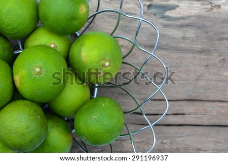Lime in steel basket on a wooden table.