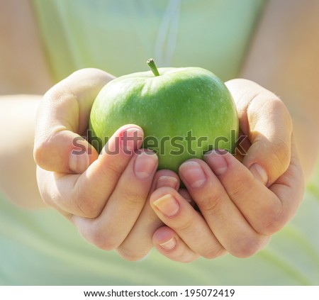 The big green apple in beautiful female hands