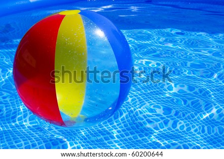 Multicolored beach ball floating on a sparkling blue swimming pool