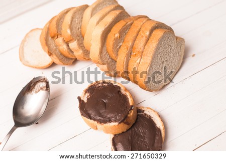 chocolate paste spread on bread on a white wooden table