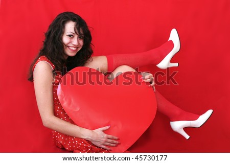 Beautiful young woman  holding big red heart in front of red background