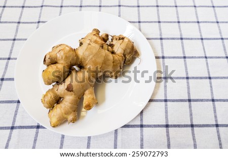 Brown Galangal Root on White Plate Placed on Big Squared Background