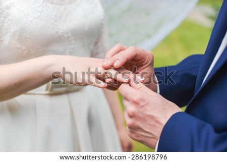 Bride putting a ring on groom\'s finger