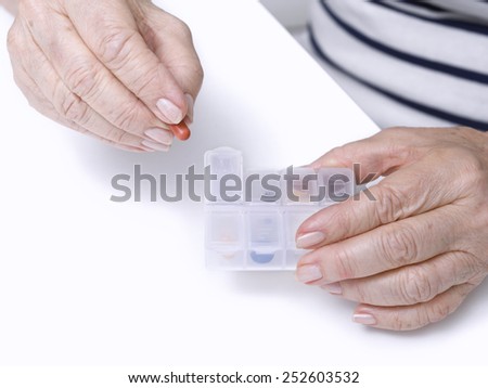 Close up of hands of an elderly woman taking a pill medicine