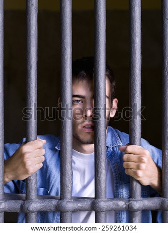 Imprisoned man, looking on the outside, seized to a few bars