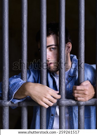 Imprisoned man, looking towards out, seized to a few bars