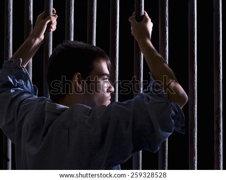 Imprisoned man, looking down, seized to a few bars