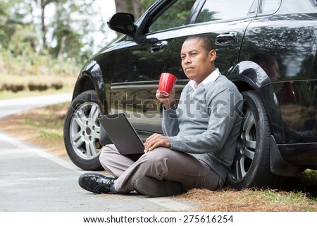 an African American man on the road enjoying your trip pauses and drinks coffee