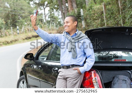 an African American man on the road next to his car taking pictures with your cell phone