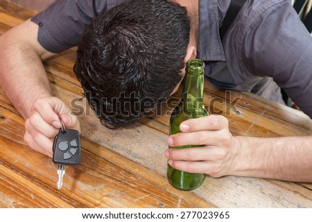 drunk man with car keys in one hand and in the other hand a bottle of beer