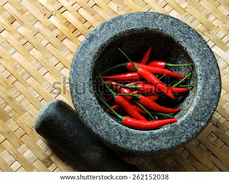 Red chillies in Mortar with Pestle. Red chillies peppers in the threshing basket texture.