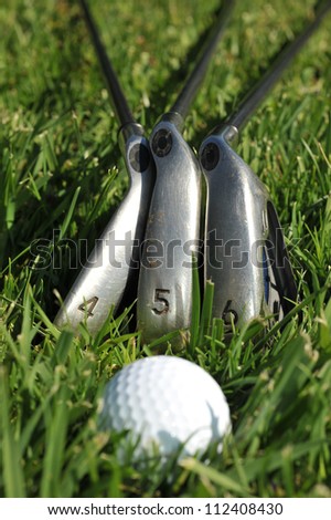 A four, five and six iron with a golf ball in grass