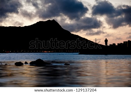 Dawn at Waikiki with silhouette of a fisherman near Diamond Head