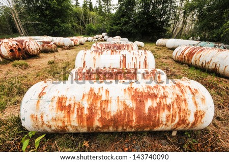 Rows of gas storage tanks lay in a field rusting