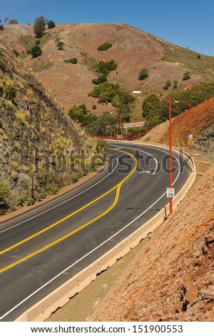 Hill with different color minerals next to a road curving by