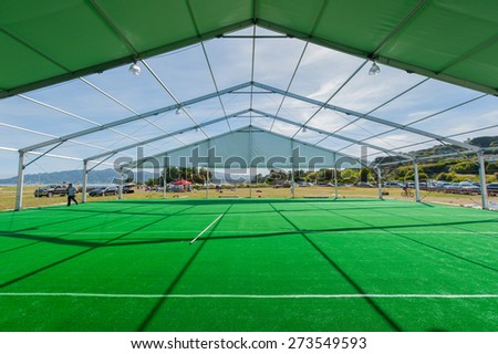A large tent in a grassy field is being constructed for a party