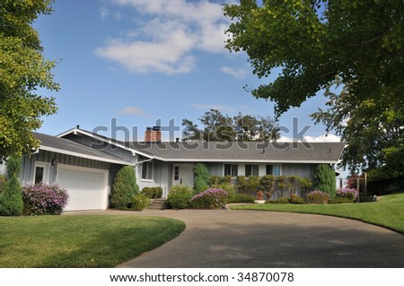 Grey house with grass and large concrete driveway
