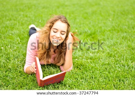 Young woman reading a book outside on the grass