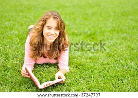 Young woman reading a book outside on the grass
