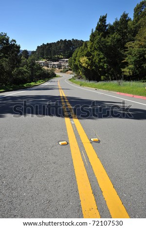 Road leads down a hill in the summer. Middle of the road life.