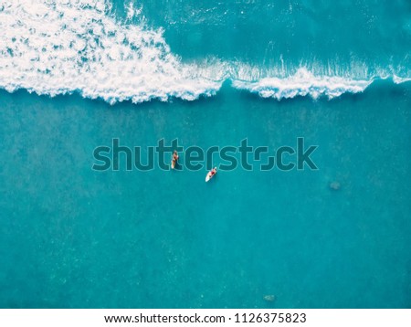 Aerial view of surfers and wave in tropical ocean. Top view