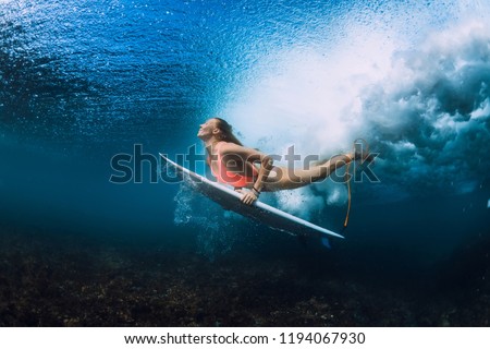 Attractive surfer woman dive underwater with under wave.