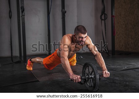 Handsome and muscular man performed exercises for abdominal muscle with roller.