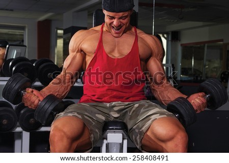 Bodybuilder biceps workout with dumbbells.
