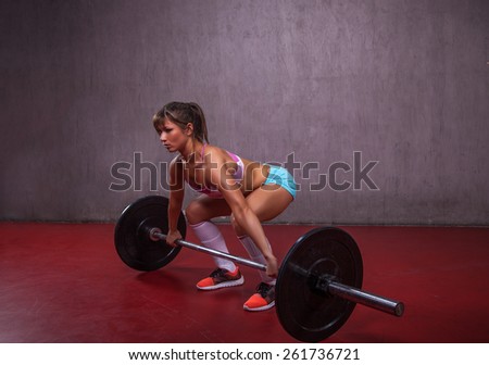Close up of a muscular athlete girl performing a squat in a gym.