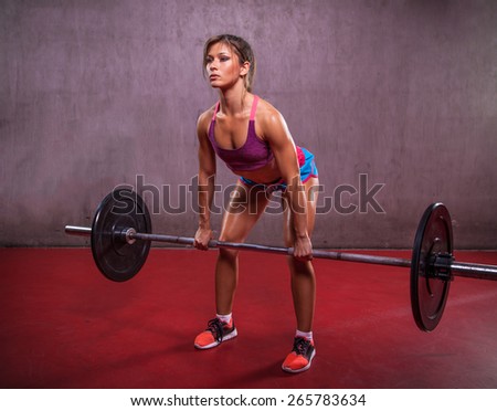 One young woman working hard in the gym.  She is lifting weights. Sport and fitness.